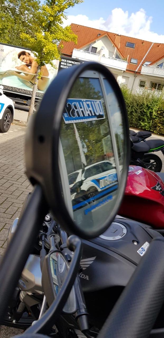Motorrad mit Spiegelung eines DU FÄHRST Fahrschulfahrzeugs